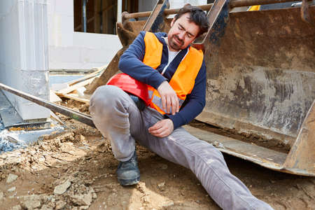 Exhausted worker or craftsman on the construction site sleeps on the excavator shovel during a breakの写真素材