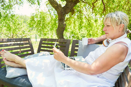 Freelance woman on laptop computer in the garden in summer with a cup of coffee