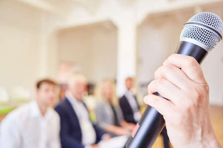 The speaker's hand holds a microphone during a presentation in a workshop or seminarの写真素材