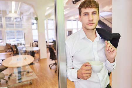 Young man as a casual start-up entrepreneur during a coffee break in the officeの写真素材