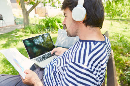 Freelancer at the laptop computer online during a project planning in the green gardenの写真素材