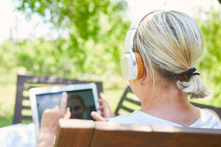 Business woman working in the garden as a home office during video conference on laptop computerの写真素材