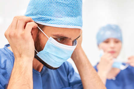 Doctor as a surgeon with hood and face mask in preparation for the operation in the clinicの写真素材