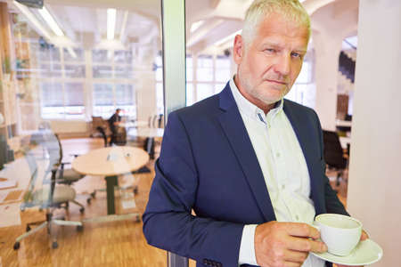 Senior businessman as a manager with experience having a coffee break in the office