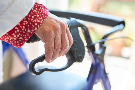 Elderly woman with hands on rollator handle at home as a symbol for disability and rehabilitationの写真素材