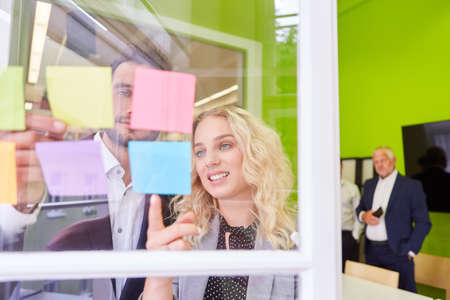Young business people brainstorming with sticky notes in creative workshopの写真素材