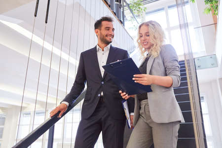 Two business people from the start-up team with clipboard in the stairwell of a companyの写真素材