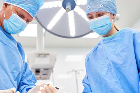 Experienced concentrated surgeon and operating room nurse during a surgical procedure in the clinic
