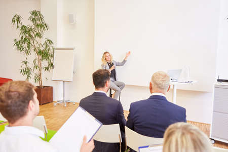 Young business woman as a speaker at a conference with an audience
