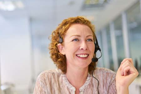 Young woman as operator with headset in the service hotline in the call center