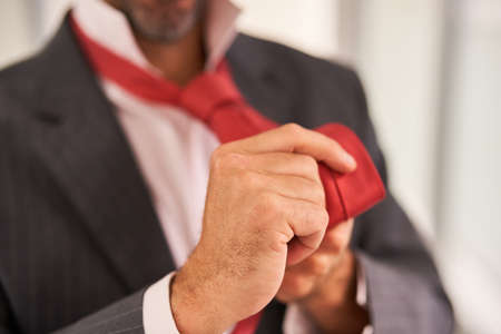 Business man tying tie in officeの写真素材