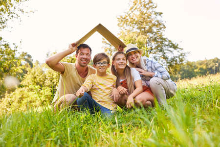 Happy family with two children with roof over their heads symbolizing house constructionの写真素材