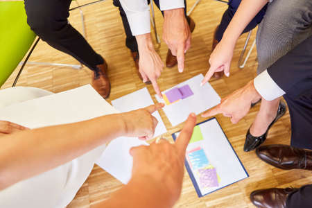 Group of business people in circle in ideas workshop while brainstorming with sticky notesの写真素材