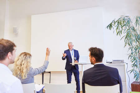 Speaker with microphone and audience giving a lecture in the lecture hall at a conference