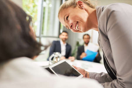 Smiling business woman using tablet computer online at a project meeting in conference roomの写真素材