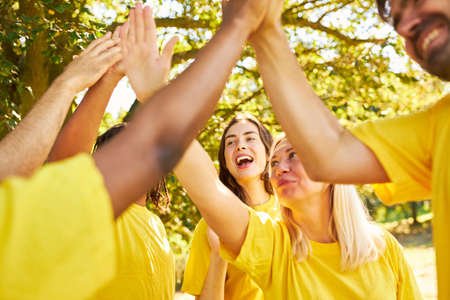 Team as a group makes high five for motivation during team building exercise in summerの写真素材