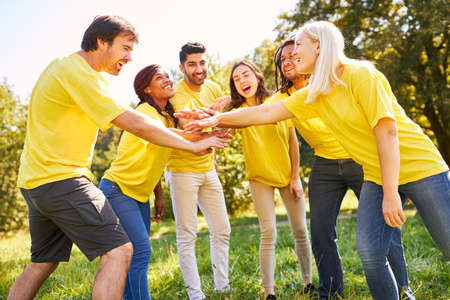 Group of young people stacking hands for motivation and team building in nature