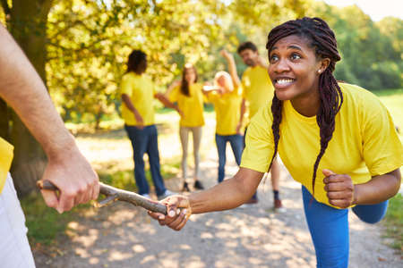 Young woman handing over the baton at a race in team building workshop