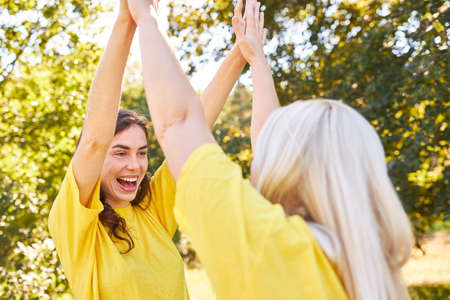 Two young women high five in a team building workshop in summer celebrating a successの写真素材