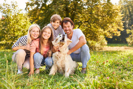 Happy family with two children and retriever dog in summer in natureの写真素材