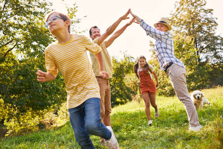 Two children run through a gate formed by parents' hands in the park in natureの写真素材