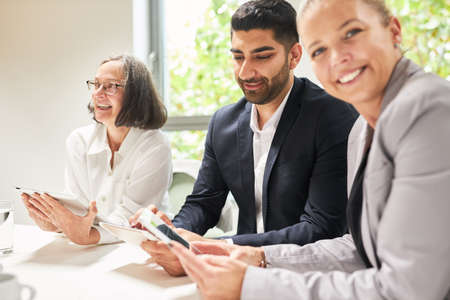 Three business people work together with tablet computers in the computer workshop in the officeの写真素材
