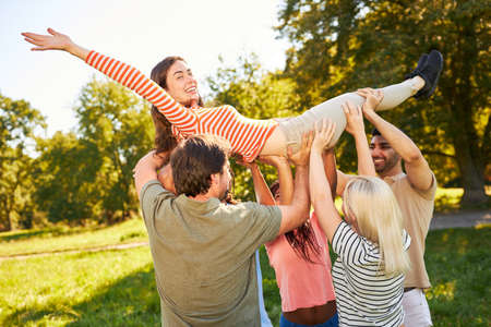 Young people lift up a woman together as an exercise in trust and cooperation