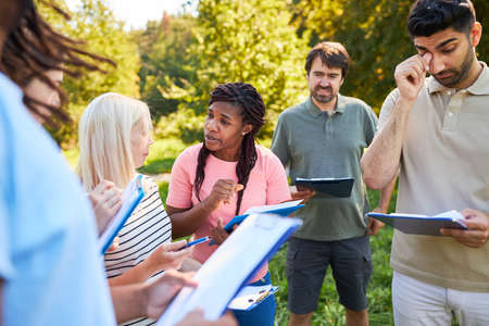 Group of young people with clipboard having a discussion in a team building workshop