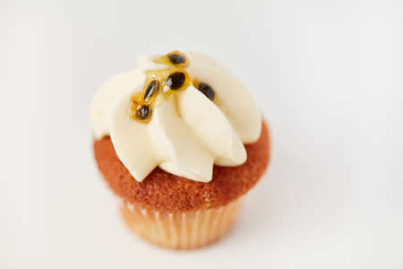 Small sweet cupcake with passion fruit cream as a decoration against a white backgroundの写真素材