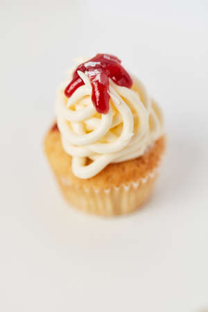 Small cupcake with spaghetti ice cream and strawberry sauce against a white backgroundの写真素材