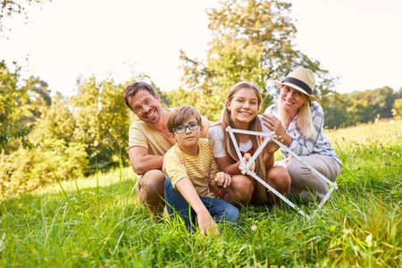 Happy family with a house folding ruler in the park in summer for home planning