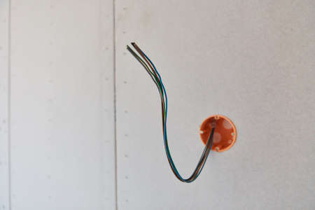 Power cables hang out on the wall in preparation for electrical installation during house constructionの写真素材