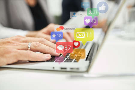 Hands of business woman on computer keyboard with colorful icons as social media concept
