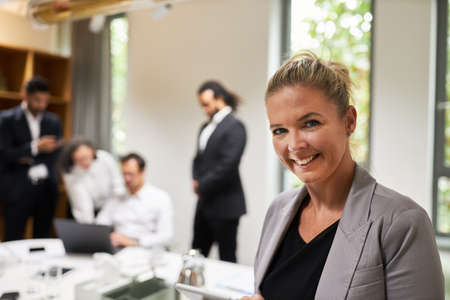 Happy businesswoman with tablet PC as a successful boss in front of her start-up team in the meeting