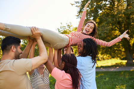 Group of multicultural people carries young woman together during a team building exercise