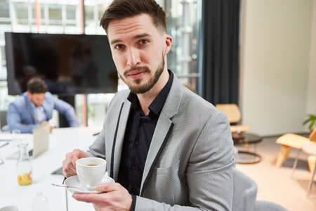 Young business start-up founder drinks a cup of coffee in the office on a breakの写真素材
