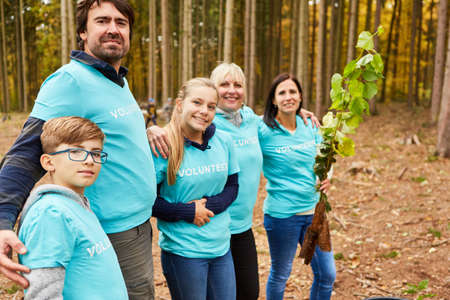 Happy family as an environmentalist team with seedling at a reforestation campaign in the forest