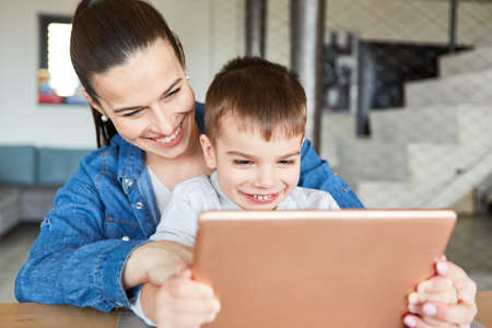 Mother and son video chatting together on computer with relatives or grandparentsの写真素材