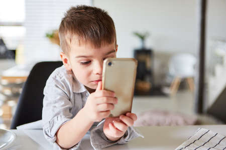 Little boy reads a text message on the smartphone or on social mediaの写真素材