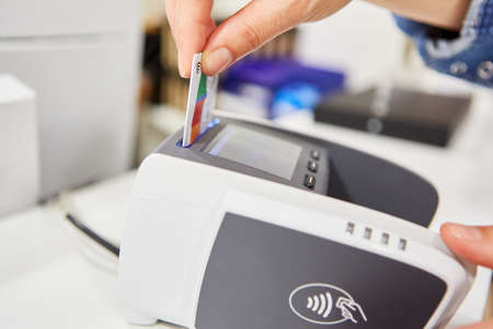 Hand inserts customer card or credit card into a card terminal for cashless paymentの写真素材