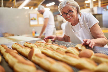 Senior baker with experience in baking Berlin pancakes in the bakeryの写真素材