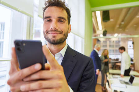 Young businessman uses smartphone app or sends a text message in the office