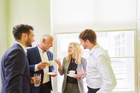 Business team with boss and trainees having small talk during a coffee break in the officeの写真素材