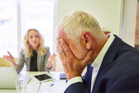 Elderly businessman with hands in front of his face for despair and overload