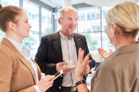 Business people having casual small talk on a coffee break in the office after a meeting