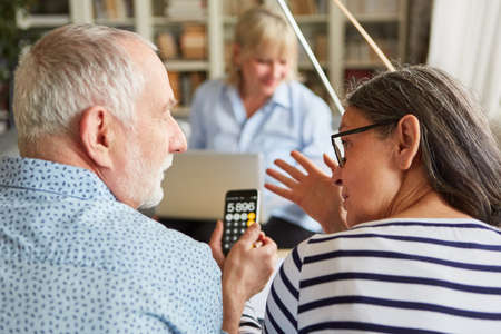 Couple of seniors with pocket calculator plans investment for retirement in a financial consultationの写真素材