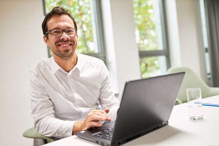 Happy businessman works as programmer on laptop computer online in office