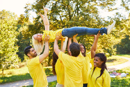 Group of young people lifts woman up together at a team building workshopの写真素材