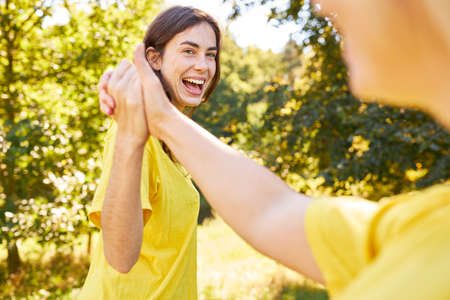 Laughing young woman doing shake hands or high five for motivation and success in summer