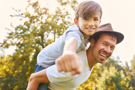 Happy single father piggybacking his son and having fun in natureの写真素材